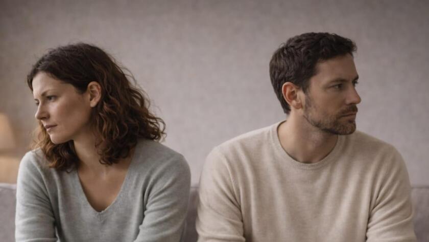 Pareja sentada en el sofá, con distancia emocional y tensión silenciosa